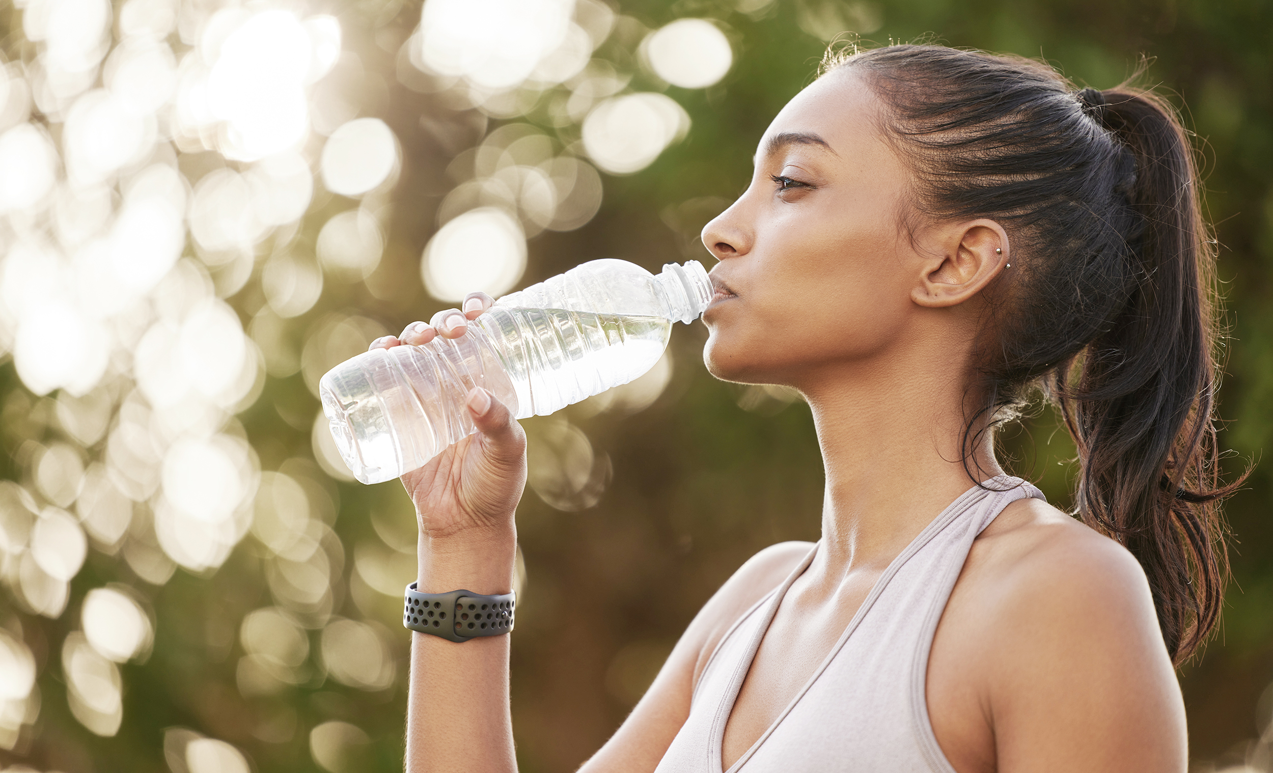 Shot of a sporty young woman drinking water while exercising outdoors